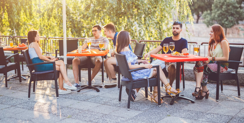 Young people relaxing in the patio section of a pub over a cold drink and a tasty snack